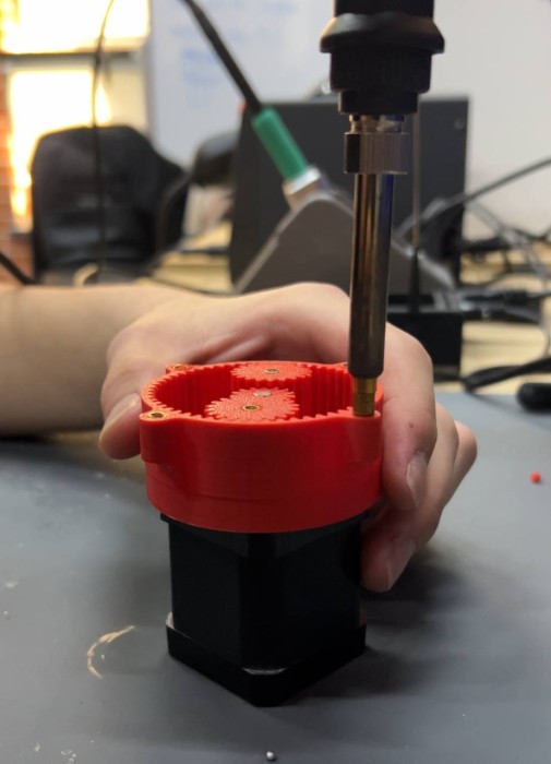 Installing brass M3 heat-set inserts into 3D printed housing using a soldering iron — close-up showing the insert being pressed into the printed hole with a brass tip