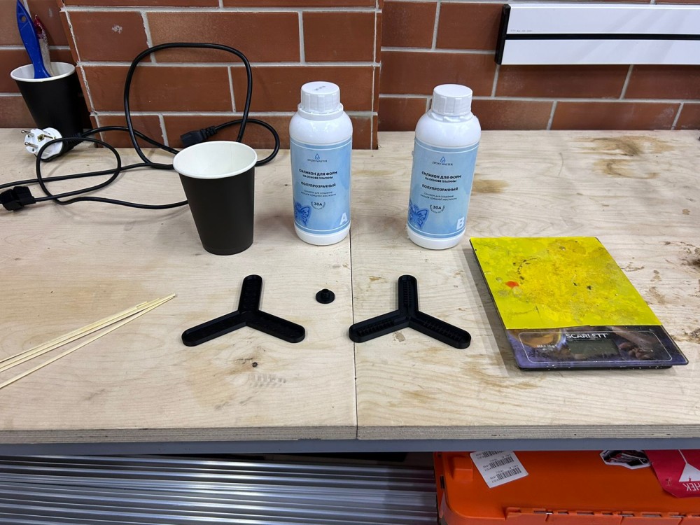 Part A and Part B silicone components, mixing cup, mold halves, and digital scale laid out before casting