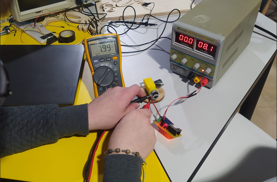 Fluke 117 multimeter measuring 7.99V across the motor terminals