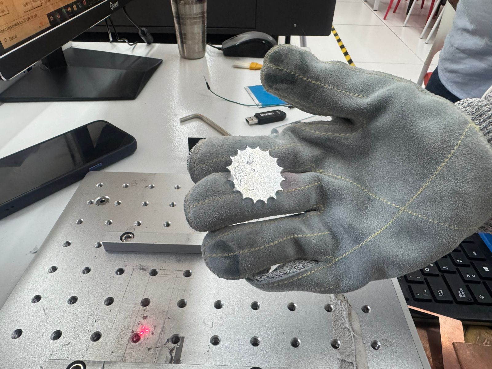 Final aluminum keychain held with a protective glove